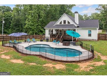 Backyard pool area with patio, lounge chairs, and a view of the home's deck and well-maintained lawn at 5745 Westwood Dr, Cumming, GA 30040