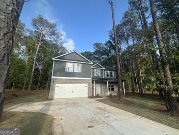 Two-story home featuring a gray facade, a brick-accented front, and an attached two-car garage with a long concrete driveway at 142 Tye St, Stockbridge, GA 30281