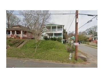 Charming two-story home featuring double balconies and a lush, green lawn on a tree-lined street at 415 Hopkins Sw St, Atlanta, GA 30310