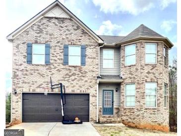 Two-story brick home with a basketball hoop, attached garage, and a welcoming blue front door at 413 Atlas Ct, Locust Grove, GA 30248