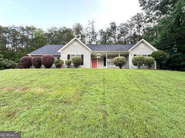 Charming ranch-style home featuring a well-manicured lawn, gray siding, black shutters, and a welcoming red front door at 9124 Comstock Ct, Covington, GA 30014