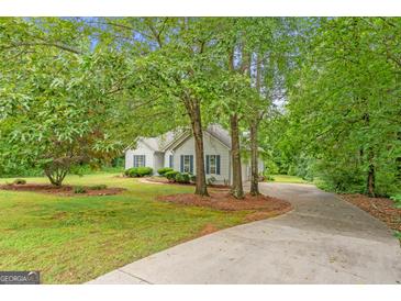 Charming home exterior featuring blue shutters, lush landscaping, and a long driveway, nestled among mature trees at 40 Wenham Ln, Sharpsburg, GA 30277