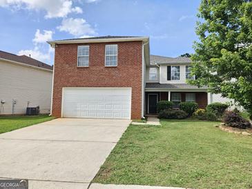 Charming two-story home with a brick front, attached garage, and well-maintained lawn at 1110 Saint Phillips Ct, Locust Grove, GA 30248