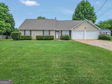 Charming single-story home featuring a manicured lawn, trimmed hedges, and a two-car garage at 130 Belmont Trl, Covington, GA 30016