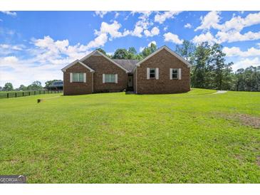 Charming brick home with lush green lawn, complemented by well-maintained landscaping and a serene countryside backdrop at 3950 Chattahoochee Rd, Cumming, GA 30041