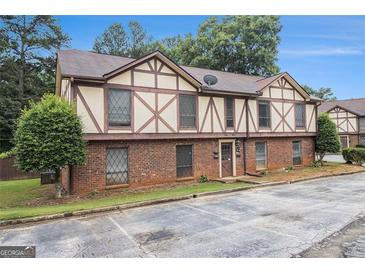 An exterior view of a brick Tudor-style townhome with mature landscaping at 3232 Abbeywood Dr, Decatur, GA 30034