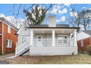 Charming grey brick home featuring a covered front porch with white railings and supporting columns at 1030 Westmoor Nw Dr, Atlanta, GA 30314
