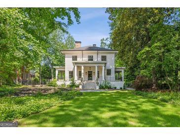 Stately two-story home with classic white columns and a lush green lawn surrounded by mature trees at 818 Springdale Ne Rd, Atlanta, GA 30306