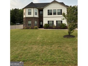 Charming two-story home features a manicured lawn and classic design with a brick and white facade and black shutters at 175 Bridgemill Dr, Covington, GA 30014