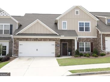 Charming townhome features a two-car garage, stone accents, and a well-manicured front lawn at 2845 Long Shadow Ct, Snellville, GA 30078