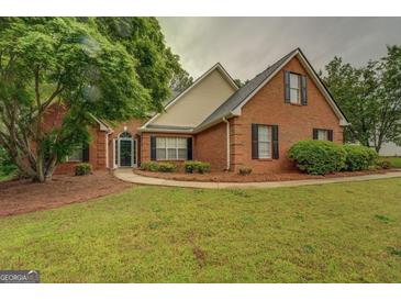 Charming brick home featuring a well-manicured lawn, mature trees, and a welcoming entrance at 1917 Kevin Se Dr, Conyers, GA 30013