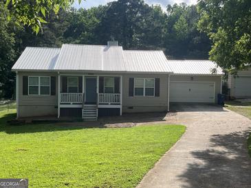 Charming single-story home with a metal roof, a front porch, an attached garage, and a driveway at 5761 Hancock Dr, Social Circle, GA 30025