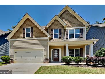 Charming two-story home showcasing a well-maintained lawn, a two-car garage, and a welcoming front porch area at 473 Cherry Creek Dr, Loganville, GA 30052