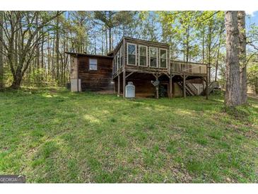 Exterior view of a rustic home featuring a wood exterior and a spacious yard at 655 Sunset Dr, Locust Grove, GA 30248