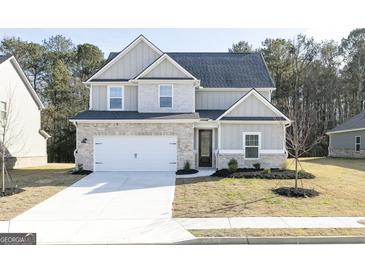 Charming two-story home featuring a brick and gray exterior, a two-car garage, and a well-manicured front yard at 3392 Arabian Farm Ln, Dacula, GA 30019