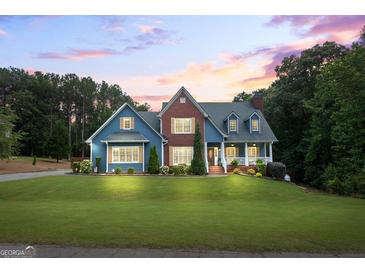 Charming two-story home featuring a brick facade, blue siding, lush lawn, and manicured landscaping at 150 Surrey Chase Dr, Social Circle, GA 30025