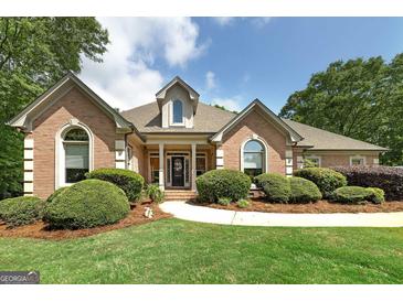 Charming brick home with manicured landscaping, pathway and arched windows at 715 Branchview Ct, Mcdonough, GA 30252
