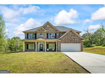 Inviting two-story brick home with a welcoming front porch, attached garage, and well-manicured lawn at 634 Gardner Rd, Stockbridge, GA 30281
