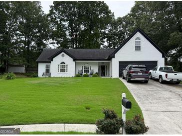 Charming white home with a manicured front yard, a covered entryway, and an attached two-car garage at 1612 Cagle Ct, Lawrenceville, GA 30045
