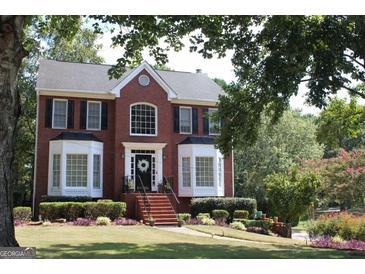Charming red brick two-story home with a well-manicured lawn and nicely landscaped flower beds at 9342 Carillon Ct, Jonesboro, GA 30236