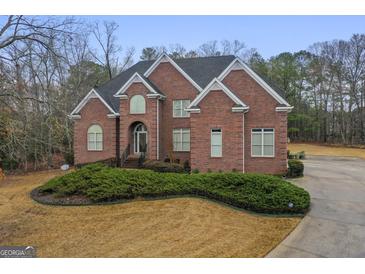 Stately red brick home featuring manicured landscaping, a well-maintained lawn, and classic architectural details at 1442 Swiftwater Cir, Mcdonough, GA 30252