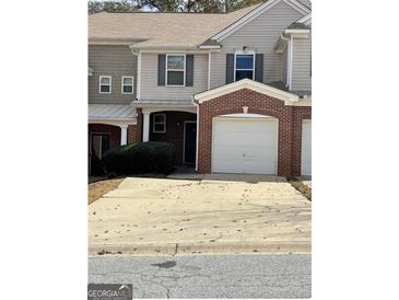 Two-story townhome with a brick garage and covered front porch, offering a convenient parking solution at 106 Ne Ellis Dr # 106, Conyers, GA 30012