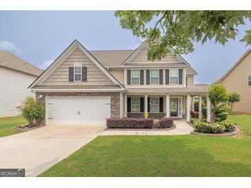 Charming two-story home with a well-manicured lawn, two-car garage, and inviting front porch at 3338 Gardenside Walk, Loganville, GA 30052