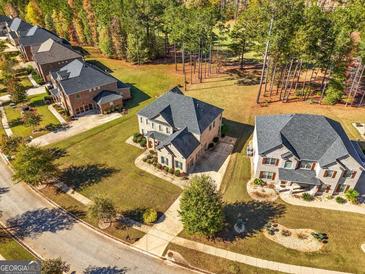 Expansive aerial view of a brick home with a lush lawn backing onto a wooded area in a desirable neighborhood at 6857 Louis Dr, Locust Grove, GA 30248
