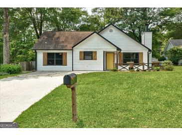 Charming white bungalow with a yellow door and a neatly manicured lawn at 203 First Leaf, Peachtree City, GA 30269