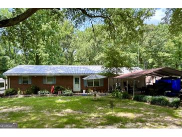 Charming single-story home with a brick facade, metal roof, and a spacious, green lawn and mature trees at 3683 Miller St, Lithia Springs, GA 30122