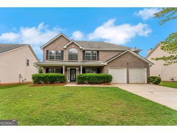 Charming two-story brick home with a well-manicured lawn, black shutters, and a two-car garage at 907 Brisley Cir, Hampton, GA 30228