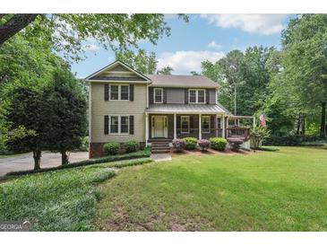 Charming two-story home with a welcoming front porch and a well-manicured lawn at 10875 Shagbark Trl, Roswell, GA 30075