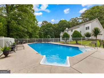 Inviting in-ground pool with a diving board and surrounding patio space, perfect for outdoor entertaining at 607 Lees Mill Rd, Fayetteville, GA 30214