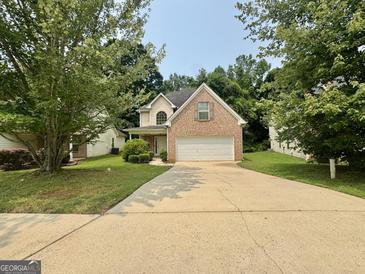 Traditional brick-accented home featuring an attached two-car garage and a well-manicured front lawn at 105 Avonwood Cir, Locust Grove, GA 30248