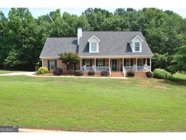 Charming brick home with a lush green lawn and inviting front porch nestled among mature trees at 500 Hayfield Ct, Locust Grove, GA 30248