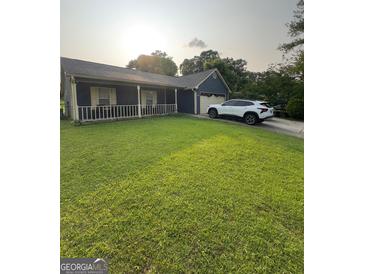 Charming single-story home with well-manicured lawn, front porch, and attached garage on a sunny day at 6403 Heritage Run, Morrow, GA 30260