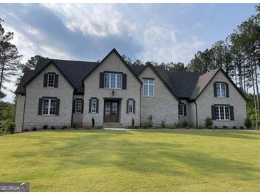 Charming two-story home with a landscaped yard and classic brick facade under a cloudy sky at 100 Regina Ct, Fayetteville, GA 30215