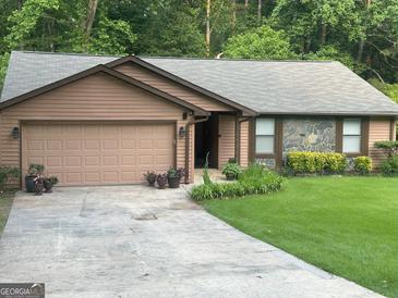 Ranch home with brown siding, stone accents, attached garage, and landscaped front yard at 6884 Shangrila Way, Riverdale, GA 30296