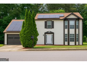 Inviting two-story home featuring solar panels, a garage, and neatly manicured landscaping at 3255 Hunters Crossing Pt, Lithonia, GA 30038