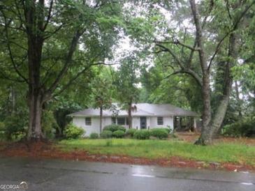 Charming one-story home with mature trees and a well-maintained lawn and white painted brick at 1726 Centra Villa Sw Dr, Atlanta, GA 30311