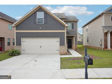 Charming two-story home featuring gray siding, a two-car garage and nicely manicured lawn at 2493 Oakleaf Rdg, Lithonia, GA 30058