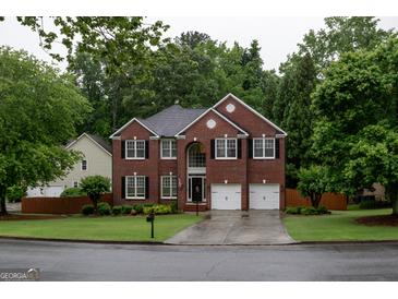Stately brick home featuring a two-car garage and manicured front lawn at 8035 Magnolia Way, Roswell, GA 30075