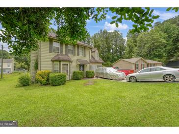 Two-story home with a well-maintained lawn and mature trees in a suburban setting with two parked cars at 3570 Keels Ln, Atlanta, GA 30349
