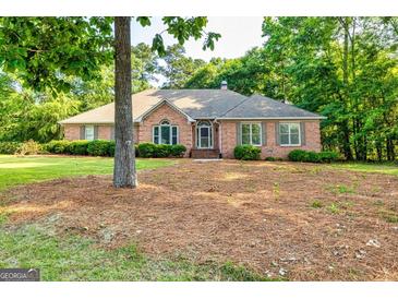 Charming brick home featuring well-maintained landscaping, arched window, and mature trees at 195 Youngs Cir, Fayetteville, GA 30215