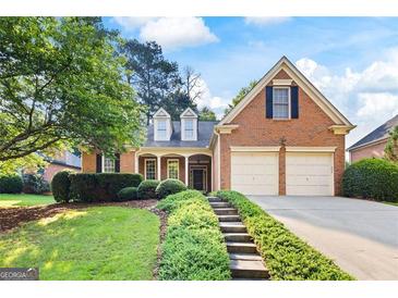 Charming brick home featuring a well-manicured lawn and two-car garage at 795 Lake Medlock, Alpharetta, GA 30022
