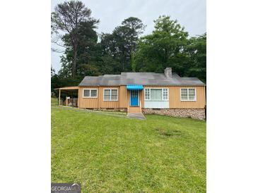 Charming single-story home featuring a quaint blue door and complemented by a well-maintained, expansive lawn at 5094 Covington Hwy, Decatur, GA 30035