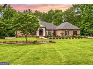 Stunning brick home with lush landscaping, mature trees, and a sprawling green lawn at 150 Old Plantation Way, Fayetteville, GA 30214