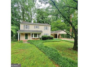 Charming two-story home with a covered front porch, carport, and lush green landscaping at 3325 Pebble Hill Dr, Marietta, GA 30062