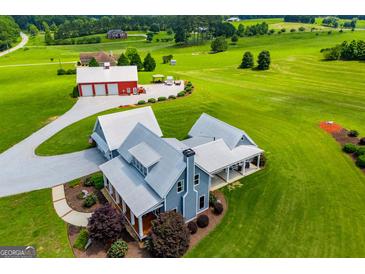 Stunning aerial view of modern farmhouse with pristine landscaping, metal roof, and a large red barn at 385 Liberty Church Rd, Carrollton, GA 30116