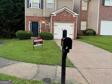 Traditional two-story home with brick and siding, featuring a one-car garage and well-maintained lawn at 5057 Windsor Forrest Lane, Atlanta, GA 30349